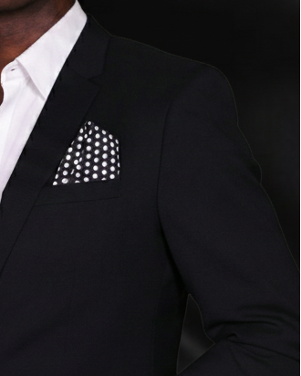 Black suit with white shirt and polka dot pocket square on a dark background